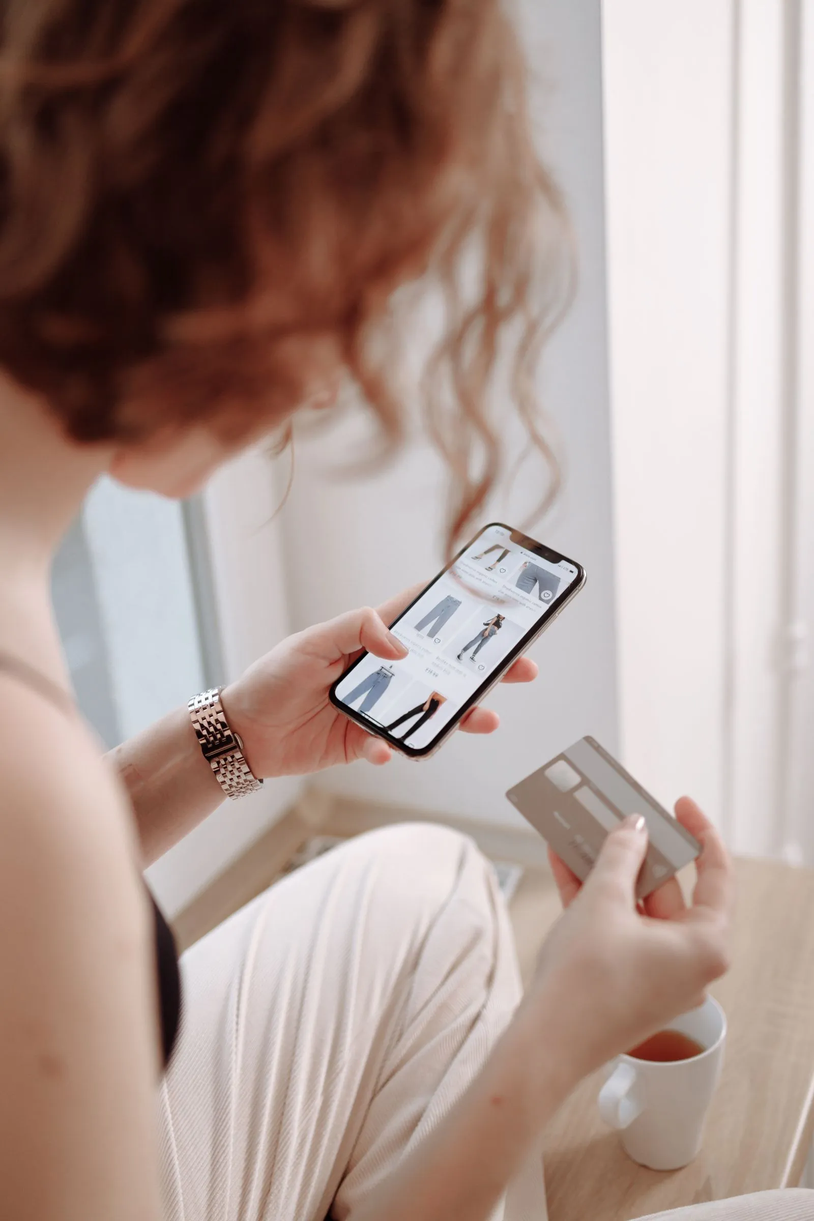 Mujer comprando ropa desde el celular con su tarjeta